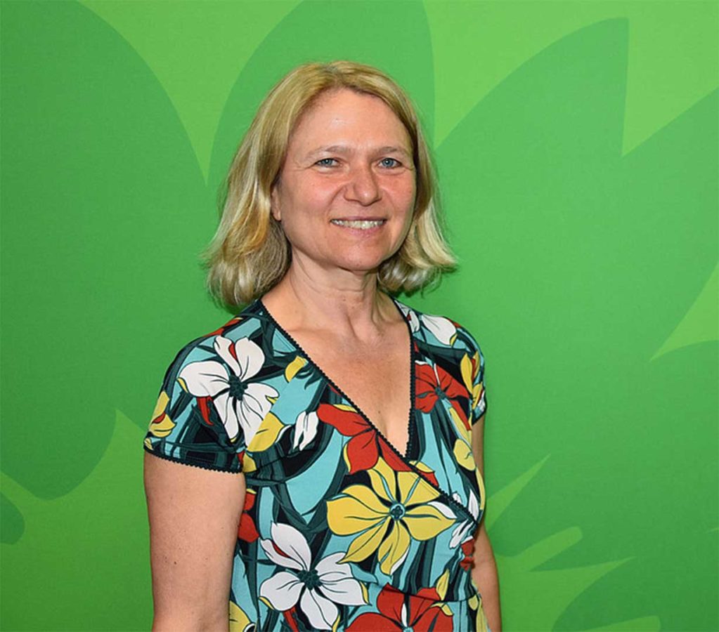 Profilbild Spitzenkandidatin Ursula Sowa vor grünem Hintergrund mit stilisierter Sonnenblume.