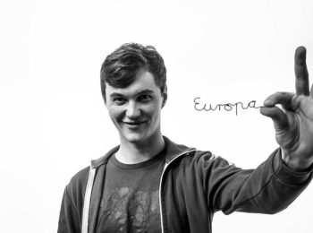schwarz/weiß Profilbild des oberfränkischen Europakandidaten Malte Gallée mit ausgestreckter Hand. Er hält der Kamera das aus Draht gebogene Wort "Europa" entgegen.
